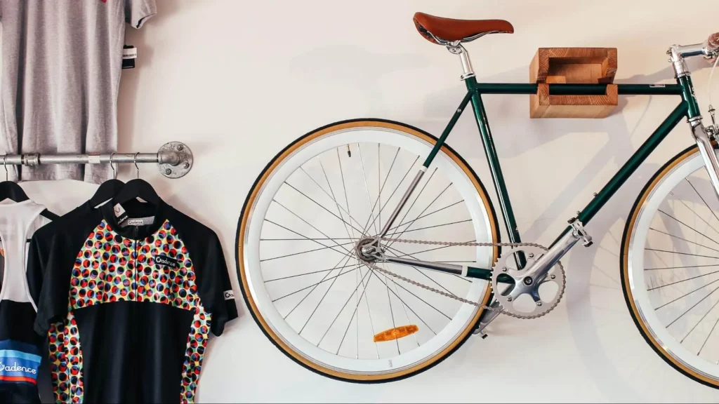 Cycling equipment hung on a wall, including a bike and cycling track tops