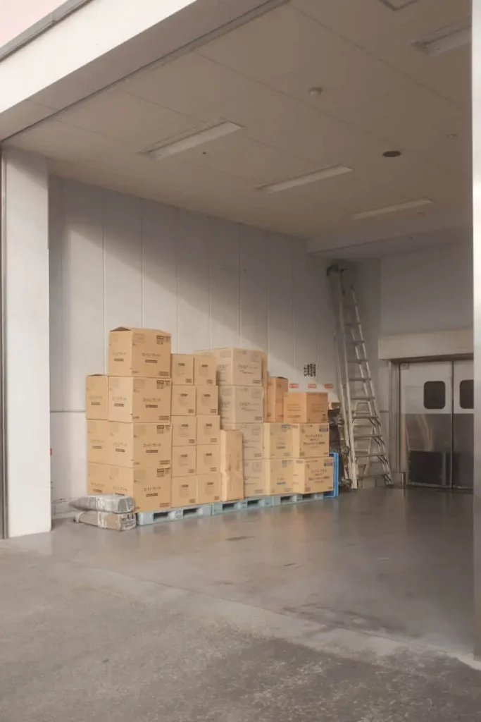 A storage unit with boxes neatly stacked on top of each other. They sit on blue wooden palettes